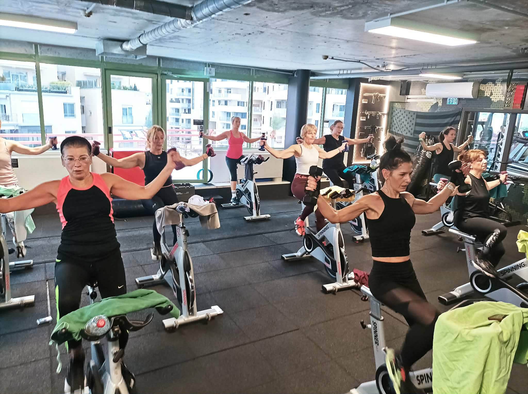 Fusion-BIKE óra: a résztvevők kézisúlyzóval erősítenek a kerékpáron ülve