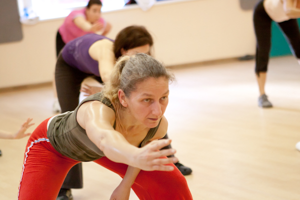 Résztvevő előrehajlásban nyújt a FitFusion óra bemelegítésén