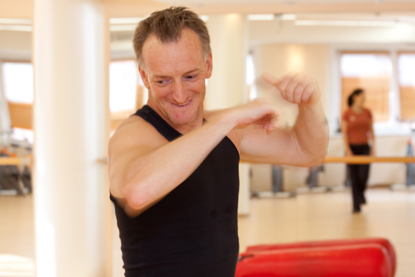 Résztvevő nevetve nyújtja a karját a FitFusion órán